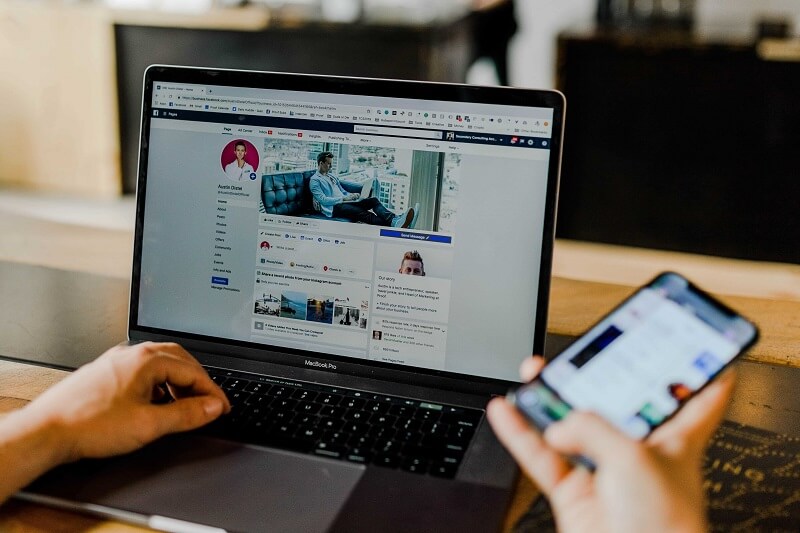 a man browsing facebook on his phone and laptop, concept of privacy risks of online ads