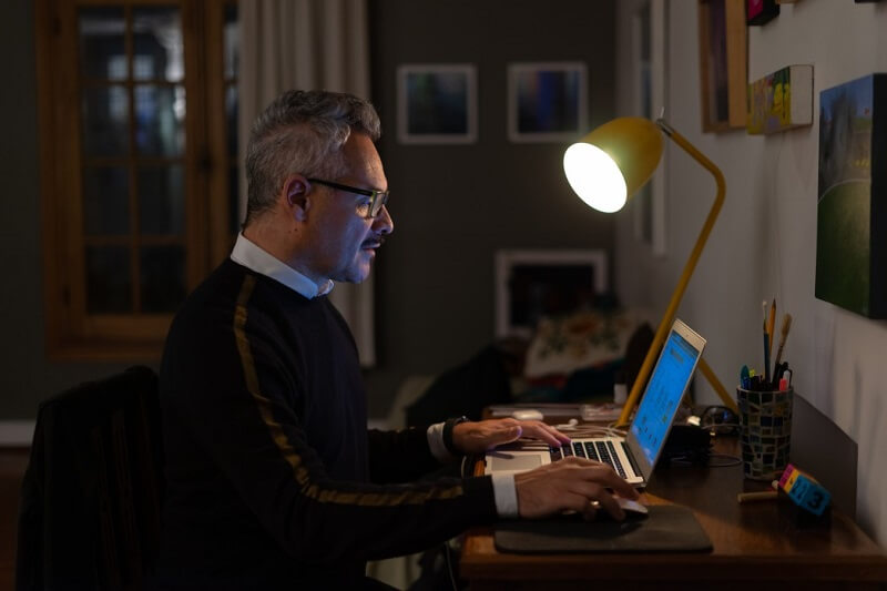 a man working on a laptop at home in the late evening