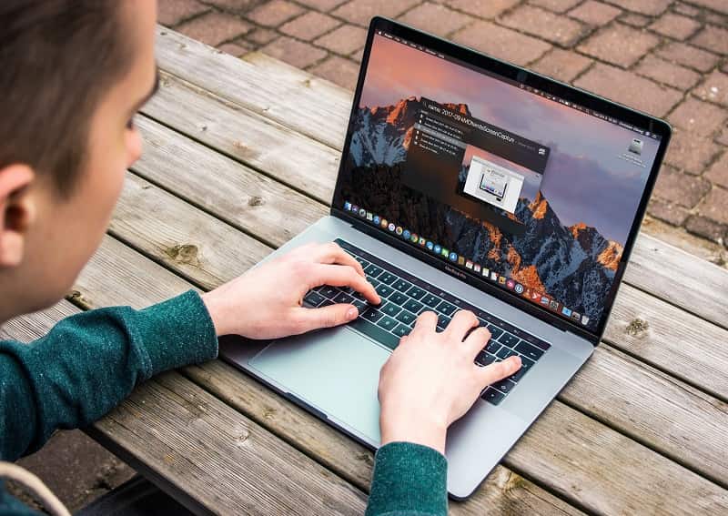 a person using a laptop, sitting outside