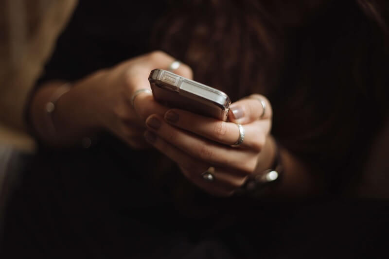 a woman holding phone, reading an SMS, smishing concept