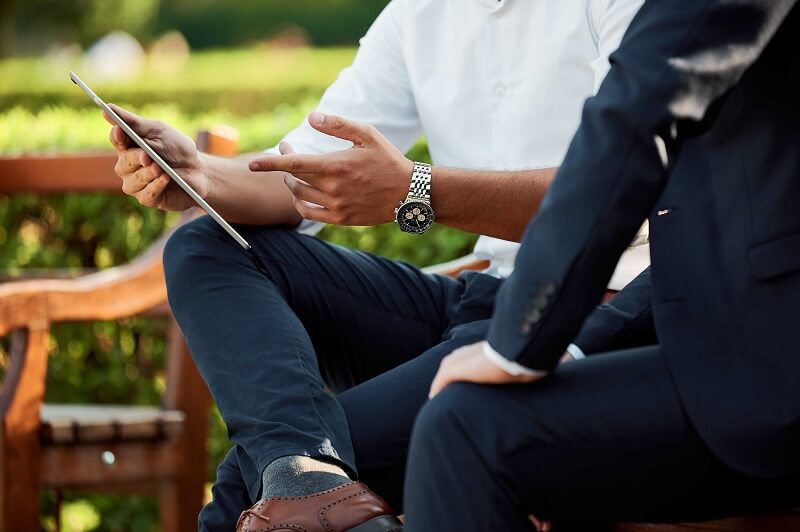 two people sitting outside and looking at a phone